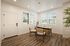 Bright home office with elegant wood flooring, large windows, and modern furnishings, perfect for remote work.