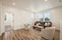 Bright and inviting living room with elegant wood flooring, modern gray sofa, and stylish armchairs, perfect for relaxation.