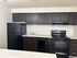 Modern kitchen featuring sleek dark cabinetry, black appliances, and ample countertop space for gourmet cooking experiences.
