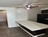 Modern apartment kitchen with sleek black appliances, spacious countertop, and warm wood flooring, featuring a ceiling fan for comfort.