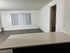 Modern apartment interior with an open living space, large window offering natural light, and a sleek countertop.
