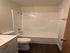 Bright and modern bathroom with a sleek bathtub, elegant fixtures, and warm wooden flooring.