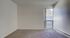 Bright and cozy room with plush carpeting and a large window offering natural light and outdoor views.
