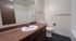 Modern bathroom with sleek dark wood vanity, polished countertop, and spacious mirror, exuding elegance and functionality.