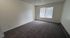 Bright and spacious room with plush carpeting and a large window for natural light.