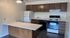 Charming open-plan kitchen with sleek dark wood cabinets, modern appliances, and a spacious breakfast bar.