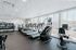 Bright and modern fitness center with state-of-the-art treadmills, stair climber, and weight equipment, featuring expansive windows for abundant natural light and city views.