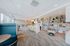 Modern and spacious open-concept lounge with stylish decor, featuring bright natural light, comfortable seating, and a chic kitchen area with contemporary shelving.