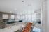 Chic and modern apartment lobby with elegant wooden staircase, glass railings, stylish lighting, and comfortable seating area.