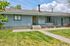 Charming ranch-style home with blue siding, welcoming front porch, and vibrant landscaping under a bright blue sky.