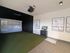 Modern recreational room featuring a golf simulator with green turf, golf-themed artwork, and sleek technology setup.