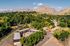 Aerial view of a charming residential complex nestled amidst lush greenery, surrounded by picturesque mountains and a serene neighborhood.