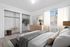 Bright and inviting bedroom with plush carpet, stylish decor, and spacious closets, perfect for comfort and elegance.