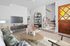 Charming living room with modern decor, featuring a cozy sofa, stylish coffee table, and sleek TV setup, with carpeted stairs leading to the upper level.