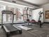 Inviting fitness room featuring modern treadmill, versatile multi-gym equipment, and bright natural lighting for an energizing workout experience.