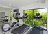 Bright, modern fitness center with treadmills, stationary bikes, and serene green views through large windows.
