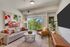 Bright and inviting living room with modern decor, cozy seating, and a large window offering lush green views of the city skyline.