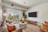 Modern living room with plush sofa, large TV, and balcony overlooking cityscape; stylish and inviting space for relaxation.