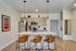 Modern kitchen with sleek appliances, stylish pendant lighting, and a chic breakfast bar with leather stools.