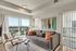 Chic apartment living room with modern decor, featuring a cozy gray sofa, vibrant throw pillows, and floor-to-ceiling windows offering a stunning city view.