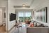 Modern living room with a cozy gray sofa, vibrant cushions, unique wooden coffee table, wall art, and a scenic balcony view.