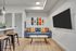 Contemporary living room with chic decor, featuring a plush blue sofa, artistic skateboard wall art, and a sleek wall-mounted TV.