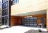 Modern apartment entrance with sleek wood paneling and a stylish glass garage door, offering ample clearance and secure bike parking.