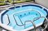 Luxurious outdoor hot tub with sparkling blue water and sleek metal railings, offering a relaxing retreat.