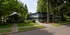 Charming apartment building surrounded by lush greenery and mature trees, offering serene living with a welcoming entrance.