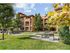 Serene apartment complex with lush greenery, outdoor seating, and communal BBQ area.