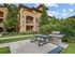 Inviting outdoor space with a modern barbecue grill and picnic area, framed by lush greenery and a charming apartment building.