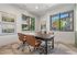 Sunlit modern office space with elegant artwork, spacious desk, and scenic window view.