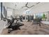 Bright and modern apartment gym featuring state-of-the-art workout equipment, large mirrors, and scenic mountain views through expansive windows.