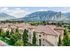 Charming apartment complex with terracotta roofs nestled amidst lush greenery and stunning mountain views.