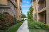 Charming apartment complex entrance with lush greenery and stone detailing.