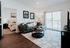 Bright, modern living room with cozy gray sofa, stylish coffee table, and inviting bedroom view through open door, enhanced by natural light from sliding glass doors.