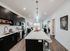 Modern open-concept kitchen with sleek dark cabinets, elegant lighting, and spacious island leading into a cozy living area, perfect for entertaining.