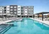 Luxurious apartment complex with a sparkling outdoor pool, stylish lounge chairs, and modern architecture, ideal for relaxation and leisure.