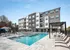 Luxurious apartment complex featuring a sparkling swimming pool with elegant lounge chairs and modern architecture.