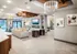 Luxurious open-concept living area featuring plush seating, modern chandeliers, chic decor, and a cozy fireplace with a view of the pool.
