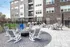 Modern apartment patio with stylish seating area, cozy firepit, and upscale outdoor grills, perfect for entertaining.