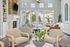 Bright and airy living room with elegant decor, stone fireplace, and large windows overlooking a poolside view.