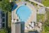 Aerial view of a luxurious circular swimming pool surrounded by elegant lounge chairs and lush greenery, offering a relaxing and inviting atmosphere.
