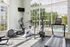 Bright fitness center with modern exercise equipment and large windows overlooking a sparkling pool.