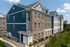 Elegant modern apartment complex with vibrant facade, showcasing a blend of brick and siding under a clear blue sky.