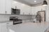 Modern kitchen with sleek white cabinetry, stainless steel appliances, and elegant pendant lighting.