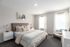 Bright and airy bedroom featuring a plush bed with cozy pillows, elegant side tables, and large windows with sheer curtains.