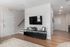 Modern apartment living area with sleek TV setup, stylish decor, inviting wooden floors, and airy ambiance.