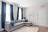 Modern living room with plush gray L-shaped sofa, blue curtains, and elegant wall art, creating a cozy ambiance.