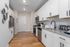 Modern kitchen with sleek white cabinets, stainless steel appliances, and elegant wood flooring.